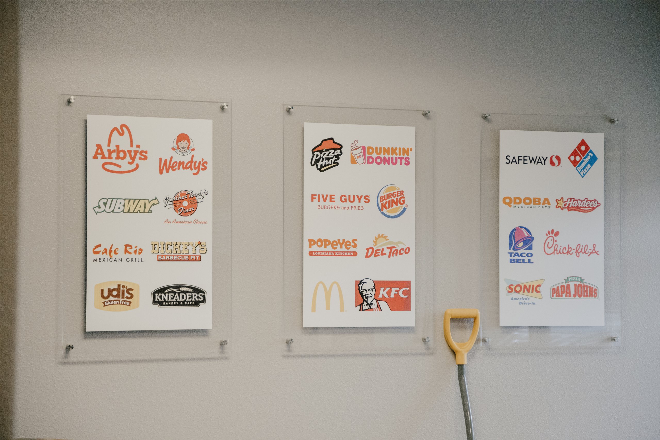 Client logos on the Maintenance Chef office wall — commercial kitchen brands serviced across Colorado